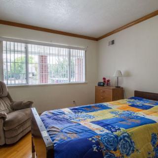 A cozy bedroom with a bed, chair, and large window allowing natural light.