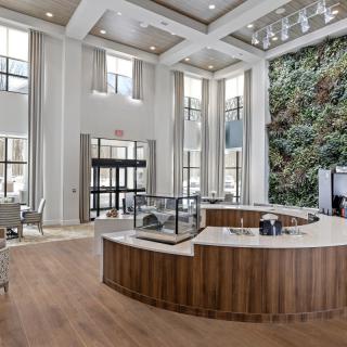 A modern lobby with high ceilings, a reception desk, and a vertical garden wall.