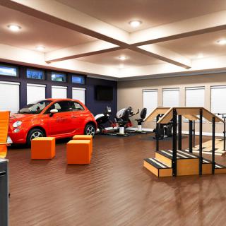 A modern room interior featuring an orange car and exercise equipment.