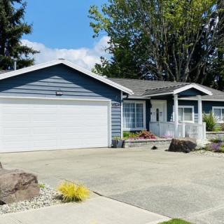 A suburban single-story house with a driveway and attached garage on a sunny day.