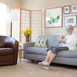 A person sitting on a sofa in a well-decorated living room, reading a book.