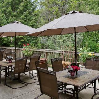 A peaceful outdoor patio with tables, chairs, and umbrellas surrounded by lush greenery.