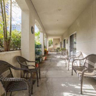 A peaceful outdoor patio with wicker chairs and greenery along a corridor.