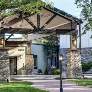 A scenic view of a building entrance with stone pillars and lush landscaping.