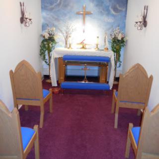 A serene chapel interior featuring an altar adorned with religious symbols and seating for reflection.