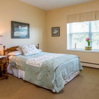 A cozy bedroom with a neatly made bed, soft lighting, and decor.