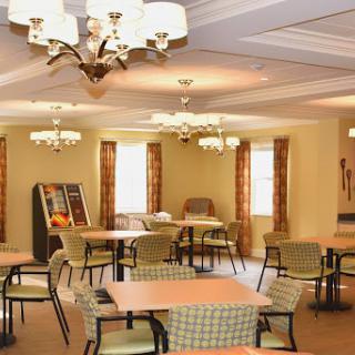 A cozy dining area with tables and chairs, illuminated by chandeliers, perfect for community gatherings.