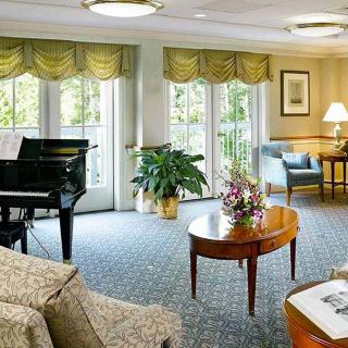 A spacious living room featuring elegant furnishings, a grand piano, and ample natural light from large windows.