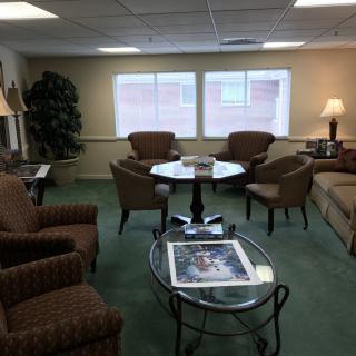 A cozy living room with sofas, chairs, and tables arranged neatly around a carpeted floor.