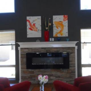 A modern living room with a stone fireplace and colorful artwork.