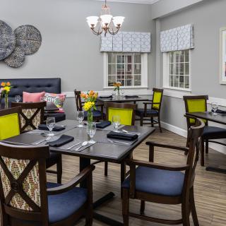 A modern dining room featuring neatly arranged tables and chairs with bright decor accents.