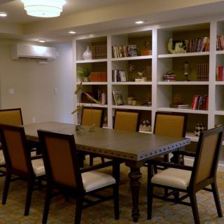 A modern conference room with a meeting table and chairs surrounded by bookshelves.