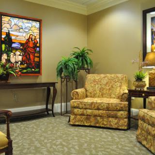 A cozy lounge area featuring patterned chairs, a table, and decorative stained glass artwork.