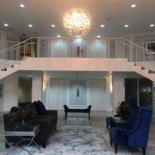 A luxurious modern living room with a grand chandelier and elegant furniture.
