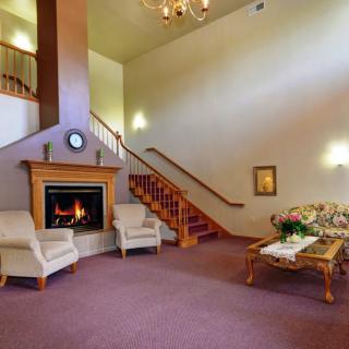 A cozy living room with a fireplace, elegant furniture, and a staircase leading to an upper level.