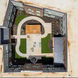 Aerial view of a square building with a landscaped courtyard at its center.