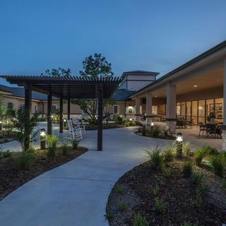 A beautifully lit outdoor garden with pathways and modern architecture at dusk.