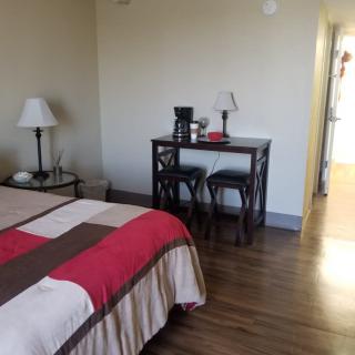 A tidy hotel room with a bed, desk, and wooden flooring.