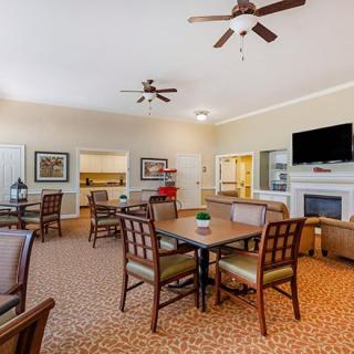 A cozy living room with dining tables, chairs, a fireplace, and a television.