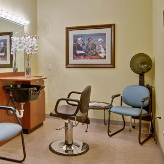 A cozy hair salon interior with chairs, a mirror, and a vintage hair dryer.