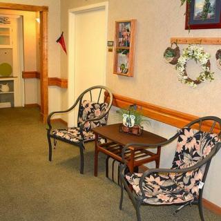 A cozy seating area in a hallway with decorative chairs, a small table, and wall decor including a wreath.