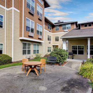 A view of a residential apartment building with an outdoor courtyard featuring a table and chairs.