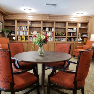 A cozy library space with a round table and chairs surrounded by bookshelves.