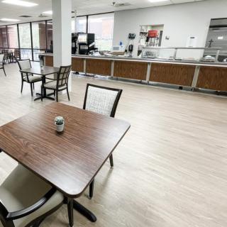 A spacious, modern cafeteria with neatly arranged tables and chairs.
