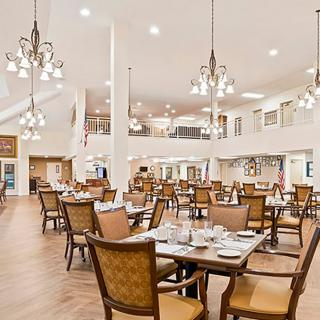 A spacious dining area with elegant chandeliers and neatly arranged tables and chairs.
