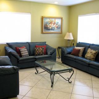 A cozy living room with sofas, a glass coffee table, decorative pillows, and wall art.