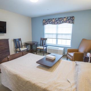 A cozy and well-furnished room featuring a bed, table, chairs, and a television.