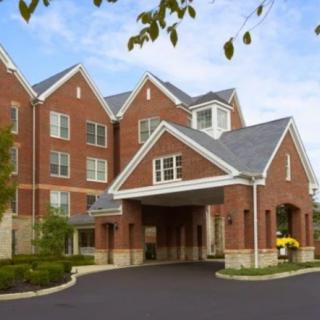 A brick residential building with a covered entrance and surrounding trees.