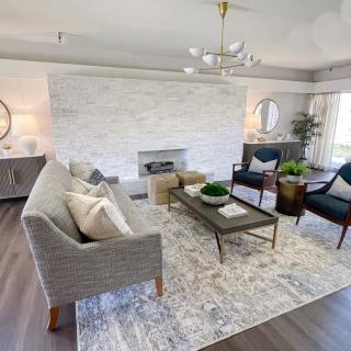 A modern living room featuring a stylish sofa, chairs, and coffee table centered around a fireplace with elegant decor.