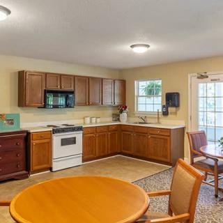 A cozy kitchen and dining area with wooden cabinets, a round table with chairs, and standard kitchen appliances.