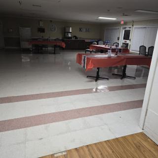 An empty indoor event space with tables set up and ready for an occasion.