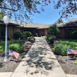 A welcoming pathway leads to a beautiful home adorned with American flags in the garden.
