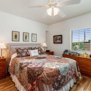 A cozy bedroom with a quilt-covered bed, wooden nightstands, and a ceiling fan.