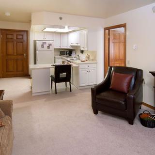 A cozy living room with an open kitchen layout, featuring comfortable furniture and a warm atmosphere.