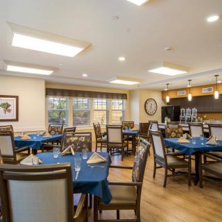 A modern dining area with neatly arranged tables and blue tablecloths, featuring overhead lighting.