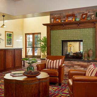 A cozy living room featuring a fireplace with green tiles and comfortable leather chairs.