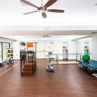 A spacious rehabilitation center equipped with exercise machines and therapy tools.