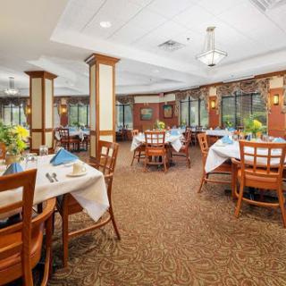 A cozy dining area featuring neatly arranged tables and chairs, complemented by natural light and elegant decor.