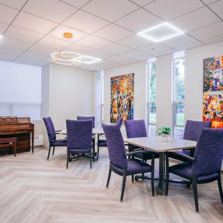 A modern dining area with tables and chairs, adorned with artwork and enhanced by stylish lighting.