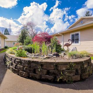 A beautifully landscaped garden with a stone wall and various plants under a partly cloudy sky.
