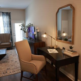 A cozy living space featuring a desk with a chair, mirror, and decorative items.
