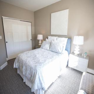 A modern bedroom with a neatly made bed, two lamps, and matching nightstands.