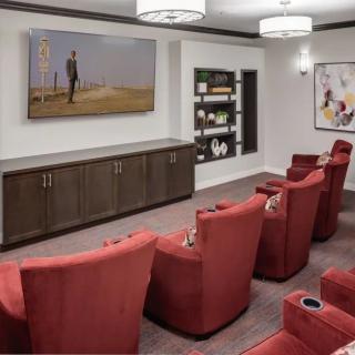 A cozy home theater room with red chairs and a large screen, complemented by artwork and modern lighting.