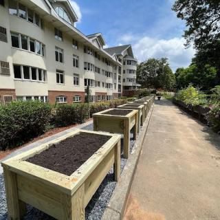 Raised planter boxes lined up along a pathway next to a building.