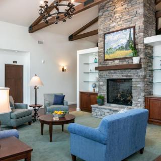 A cozy, well-decorated living room featuring a stone fireplace, comfortable seating, and elegant wood beams.
