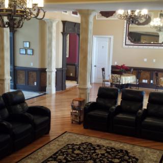 A spacious living room with leather recliner sofas and elegant chandeliers.